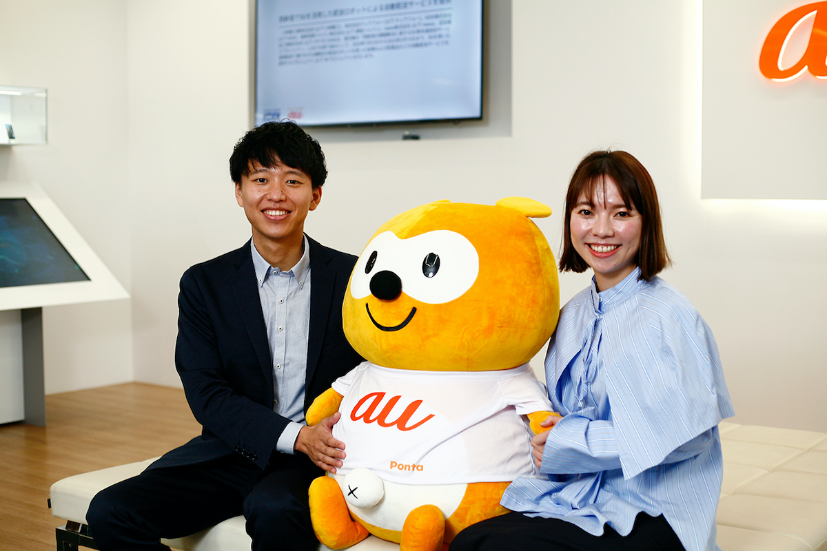 写真:auのTシャツを着たポンタぬいぐるみを挟んだおふたり
