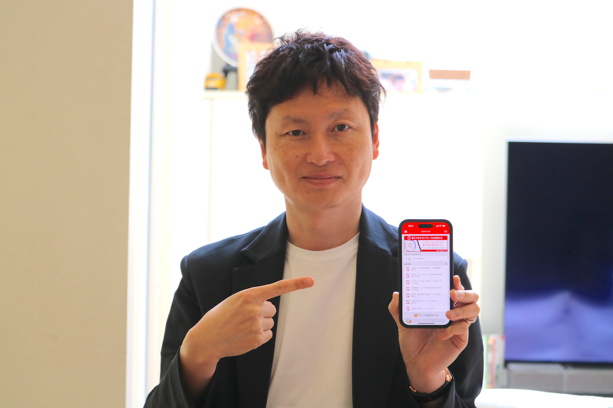 写真：auカブコム証券のアプリ画面を見せる菊地さん